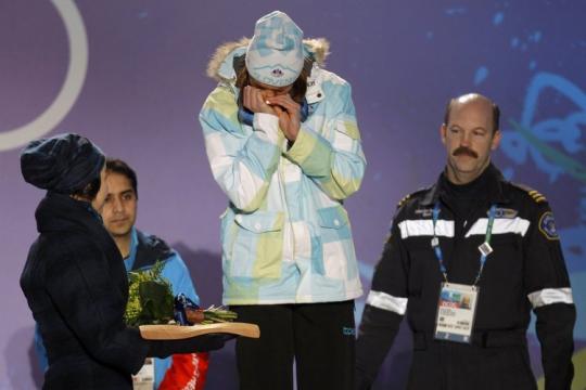 La esquiadora llorando en el podio tras necesitar ser ayudada a subir a él por dos personas. Foto de Reuters